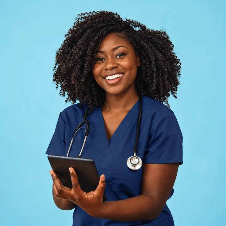 A smiling clinician in scrubs holding a tablet